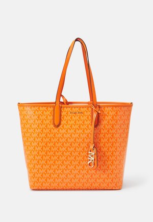 Bolso tote de Michael Kors de color naranja brillante con patrón repetido del logo MK, doble asa para el hombro y un colgante metálico con las iniciales MK en la asa.