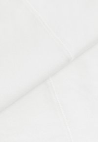 Tela de algodón blanca con una textura suave, doblada y en capas. Presenta costuras visibles a lo largo de los bordes, que proporcionan un contraste sutil.