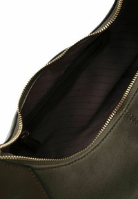 Interno di una borsa in suede verde oliva con una tasca zip e fodera marrone scuro caratterizzata da sottili motivi a righe. Dettagli della cerniera in oro.