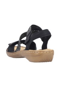 Black sandal with woven upper straps. Features adjustable Velcro closure, contoured footbed, and rubber sole without prominent patterns.