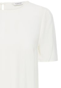 Blouse blanche à manches courtes avec un col rond et un léger détail bouffant sur les manches, avec une petite fermeture à bouton dans le dos.