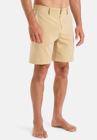 Bežové bavlněné kraťasy s plochým předním dílem, zapínáním na zip a bočními kapsami. Slim fit design, olemované okraje a žádné viditelné vzory.