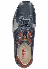 Zapato de cuero marino con acentos de ante gris y ojales de cuero marrón. Presenta perforaciones, costuras en contraste y una suela de goma.