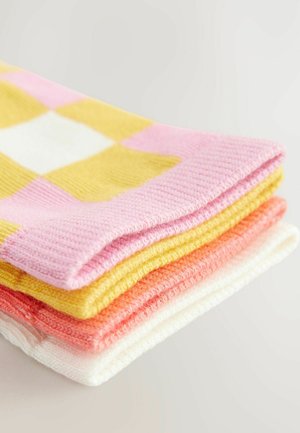 Montón de calcetines en rosa, amarillo, naranja y blanco. Presenta un patrón a cuadros, material de punto suave y una textura lisa.