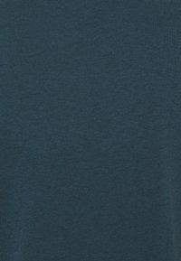 Dark teal short-sleeve t-shirt made of a soft, textured cotton blend. Features a crew neck and smooth finish, with no visible logos or patterns.