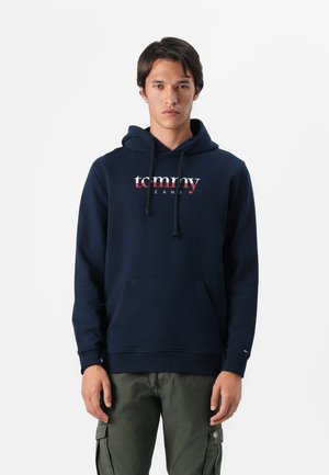 Marineblauwe hoodie van een katoenmengsel, met een voorste kangaroezak en een capuchon met trekkoord. "Tommy Jeans" logo in rood en wit over de borst.