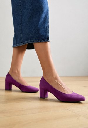 Paarse suède pumps met een ronde neus en een blokhak. De textuur oogt zacht en glad, perfect passend bij een denim rok.