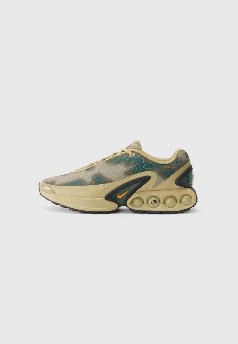 Baskets basses camouflage beige et vert avec semelle noire, coussinets de rembourrage distincts au talon, et petit logo Nike swoosh orange sur le côté.