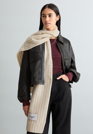 Black leather jacket with two front pockets, layered over a burgundy top. A cream scarf with vertical stripes drapes around the neck.