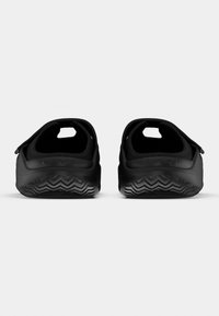 Chaussures noires à enfiler avec un talon arrondi, une semelle en caoutchouc texturée présentant un motif en zigzag, et des découpes latérales pour la ventilation.