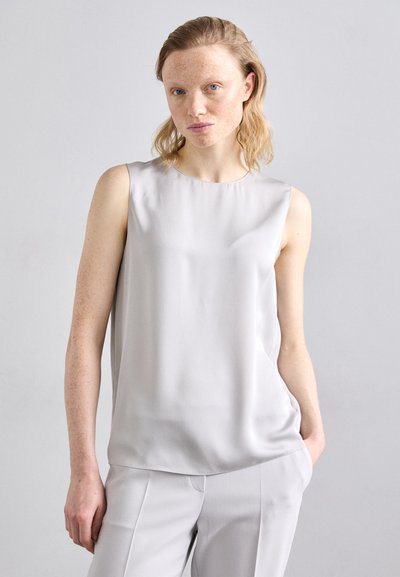 Light gray sleeveless top made of smooth fabric, featuring a round neckline and subtle draping. Paired with gray tailored pants.