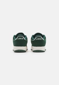 Pair of dark green and white Lakai low-top sneakers shown from the back on a white background.