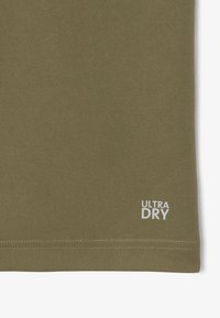 T-shirt in tessuto testurizzato verde oliva con il logo "ULTRA DRY" in bianco nell'angolo inferiore. Materiale leggero e traspirante.