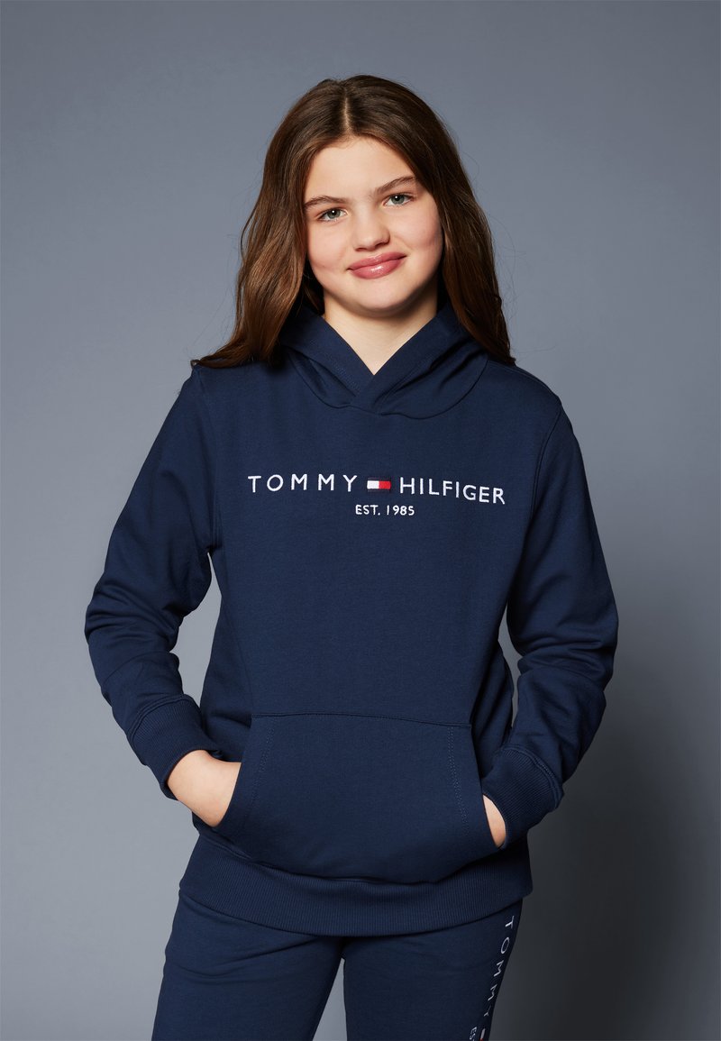 Námornícky modrá mikina s kapucňou vyrobená z jemného materiálu, s prednou kapsou a vyšitým logom "TOMMY HILFIGER EST. 1985" na hrudi.