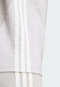 Gray athletic apparel featuring white stripes on the sides. The fabric appears soft with a smooth texture and relaxed fit.