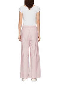 Pantalons larges à rayures roses claires avec une taille élastique et deux poches arrière, associés à un haut blanc ajusté à manches courtes.