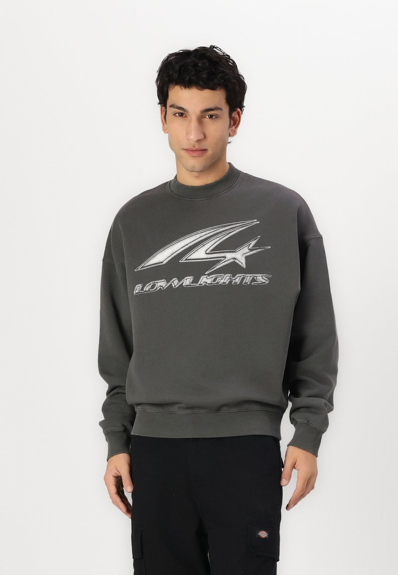Gray sweatshirt with ribbed neckline and cuffs, featuring a prominent silver logo design on the front. Soft fabric, relaxed fit.