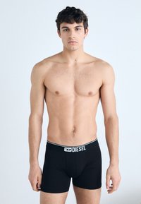 Black boxer briefs made from stretch fabric with a fitted design. Features a branded waistband and smooth texture.