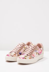 Sneakers med blommönster i rundad form, med rosa textilöverdel och beige detaljer, gummisula och öglor i roséguld.