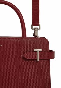 Bolso de mano texturizado en rojo con un diseño estructurado, material sintético, un asa superior y una correa de hombro desmontable con herrajes en tono plateado.