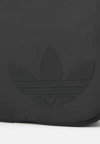 Zwarte rugzak met een getextureerd, ton-sur-ton zwart trefoil-logo en horizontale strepen, gemaakt van duurzaam materiaal met een gladde afwerking.