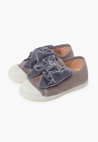 Scarpe in tela grigia con grandi fiocchi di velluto sul davanti, punte bianche in gomma e suole texture per una migliore aderenza.