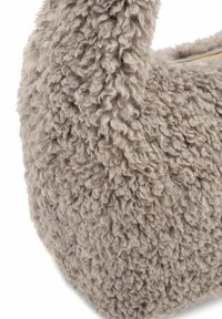Borsa in pelliccia sintetica di un beige tenue, con una superficie morbida e texturizzata con fibre arricciate e un manico curvo. Apertura con zip nella parte superiore.