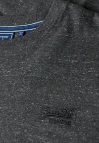 Kulgrå sweatshirt med en blød tekstur, der har en ribbet halsudskæring og et præget Superdry-logo på venstre bryst.