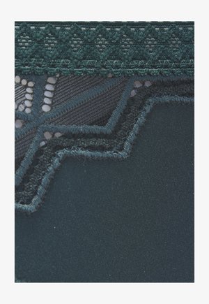 Tumši tirkīza audums ar izgreznotu mežģīņu apdari, kurā gar malu ir ziedu un ģeometriski raksti.