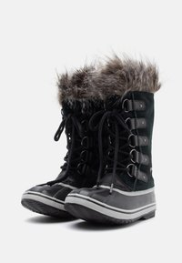 Bottes imperméables noires et grises avec garniture en fausse fourrure, design à lacets, semelle en caoutchouc texturée et cheville rembourrée pour l'isolation.