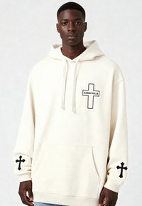 Felpa crema realizzata in morbido tessuto con tasca frontale, ricamo a croce nera sulle maniche e toppa sul petto con la scritta "KARMA KILLS."