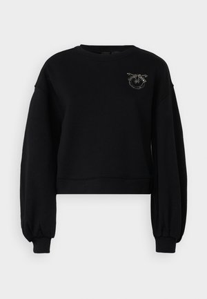 Svart cropped genser med lange, puffete ermer. Har en teksturert logo-accent med metalliske detaljer på brystet.