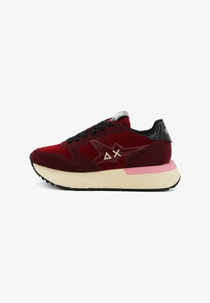 Røde ruskinds sneakers med en hvid og pink sål, sorte snørebånd og blanke detaljer. Har et logo på siden og en polstret hæl.