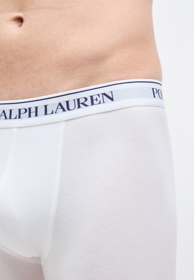 White cotton boxer briefs featuring a navy and white elastic waistband with "RALPH LAUREN" logo. Smooth texture, fitted design.
