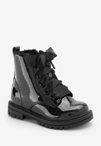 Musta kimaltava nilkkuri kiiltävällä pinnalla, pehmustettu sisus, leveät satiininaulaukset ja kestävä pohja. Sisältää koristeellista ommelta ja silmukoita.