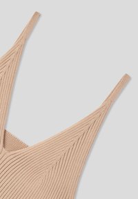 Canotta beige a coste con spalline sottili, caratterizzata da un tessuto testurizzato e un design con scollatura a V.