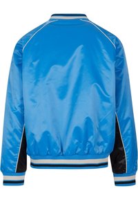 Veste bombardier bleu brillant avec panneaux latéraux noirs, passepoil blanc, et poignets et ourlet à rayures bleu, blanc et noir.