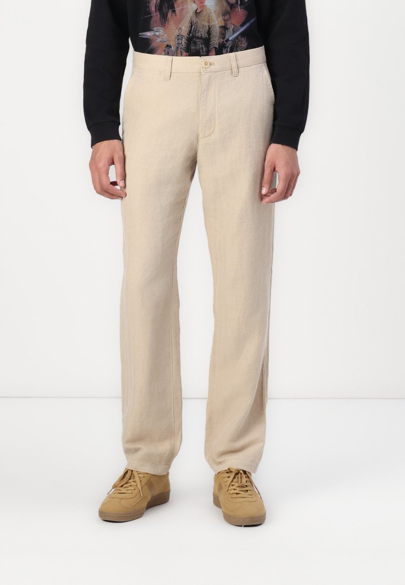 Pantaloni din in bej cu croi drept. Prezintă un sistem de închidere cu nasture în față și bretele pentru curea. Asortați cu adidași bej pentru un look casual.