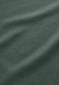 Tejido de color verde oscuro con una textura suave, que presenta un sutil patrón de tejido y una ligera caída, apto para diversas aplicaciones.