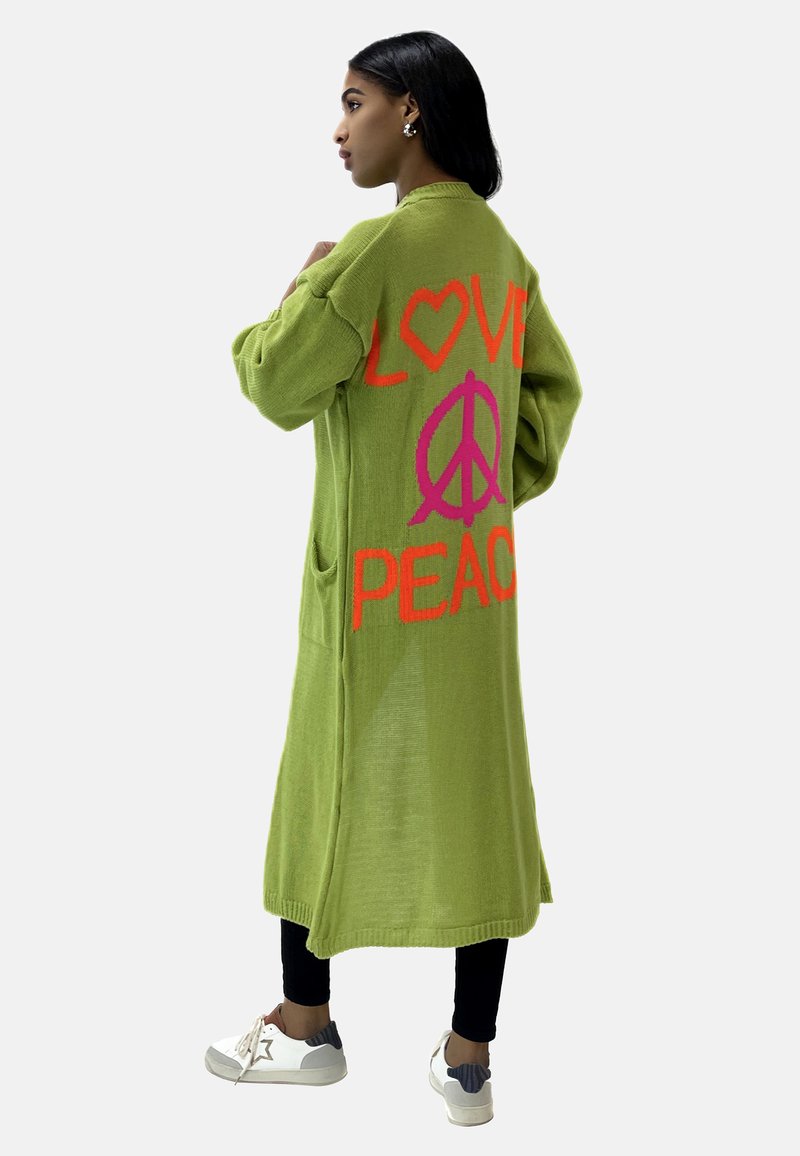 Grön cardigan med stora orange och rosa grafik med "LOVE" och fredssymboler. Lång, avslappnad passform med fickor, ribbad nederkant och mjuk textur.