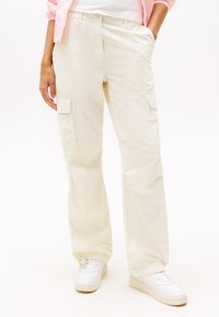 Pantaloni cargo bej cu buzunare laterale, realizați dintr-un material ușor. Design drept, cu închidere prin nasture și fermoar.