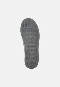 Suela de zapato de goma gris con patrones de tracción circulares y surcos. Presenta una impresión de tamaño 38 y un pequeño logo en el borde inferior.