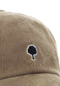 Casquette en velours côtelé marron ornée d'un logo d'arbre noir brodé, entouré de blanc. La texture du tissu est visible avec des crêtes verticales.