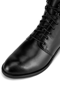Czarne skórzane buty na sznurówki z gładkim wykończeniem, okrągłym noskiem, skomplikowanym systemem sznurowania oraz wzmocnionymi oczkami dla większej trwałości.