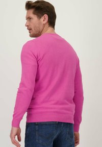 Strakke, lange mouwen trui van een heldere roze katoenmix, met geribbelde manchetten en zoom, gecombineerd met donkerblauwe spijkerbroek.