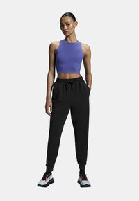 Fialový crop top, čierne jogger nohavice s elastickým pásom a multikolorové športové topánky. Elegantný dizajn, hladká textúra a kontrastné akcenty.