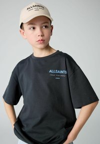Fekete pamut póló rövid ujjakkal és laza szabással, kék 'ALLSAINTS' logóval és felirattal, bézs sapkával párosítva.