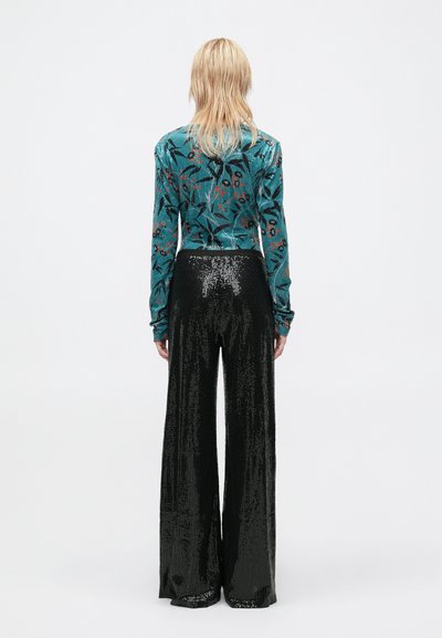 Blusa de manga longa turquesa com padrão floral, combinada com calças largas pretas com lantejoulas. Textura suave, ajustada na cintura, ajuste solto.