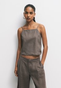 Hnědý lněný crop top s tenkými ramínky spolu s volnými hnědými lněnými kalhotami. Jednoduchý design s uvolněným střihem a minimálním zdobením.