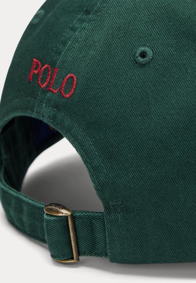 Dark green baseball cap with red embroidered "POLO" lettering, adjustable strap with metal hardware, and textured cotton fabric.